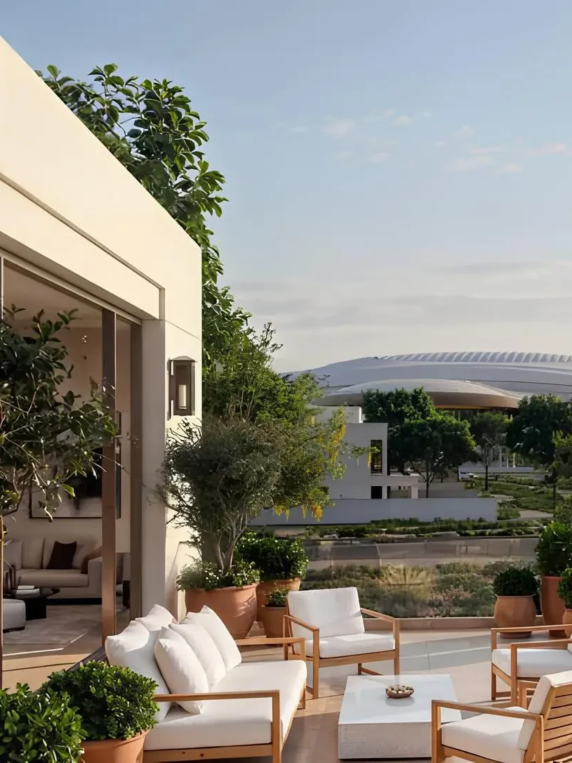A Wadeem Gardens terrace at golden hour — teak seating, terracotta planters and the district beyond